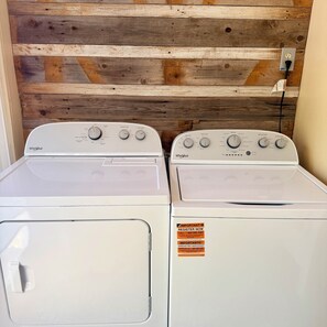 Zwei Whirlpool Waschmaschinen mit Frontlader und Bedienfeldern, eine Holzwand und eine Steckdose.