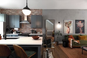 Una cocina moderna con pared de ladrillo, armarios grises y una isla central.