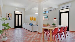 Un salon moderne avec un canapé, une table à manger, des chaises et une plante en pot.