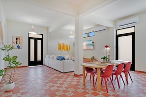 Una sala de estar moderna con sofá, mesa de comedor, sillas y una planta en maceta.