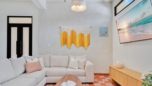 Un salon moderne avec un canapé, une table basse, un téléviseur fixé au mur et un rideau décoratif.