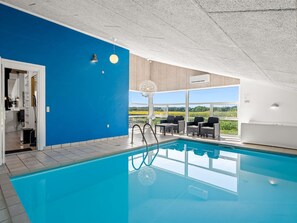 Ein Schwimmbad mit Blick auf die Landschaft, eine überdachte Sitzgelegenheit und eine Tür zu einem Zimmer.