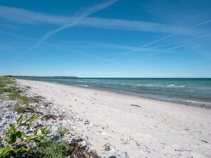 Ein Strand mit felsigem Ufer, blauem Himmel und ruhigem Meer.