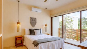 A bedroom with a bed, bedside tables, a ceiling fan, an air conditioner, and a large sliding glass door leading to an outdoor area. - Boho Apartment with Pool & Cenotes  (Tulum)