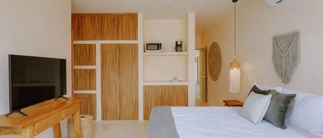 A bedroom with a TV, wooden wardrobe, bed, bedside table, and ceiling fan.