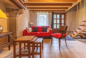 A cozy living room with a red sofa, wooden coffee table, and a chair. - Gîte chez Luc - SAINT FLOUR L'ETANG (SAINT FLOUR L'ETANG)