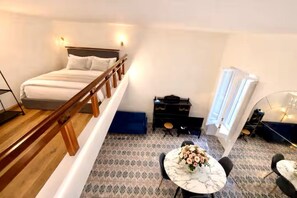 A bedroom with a bed, wooden railing, a small table with flowers, a piano, and a window. - Shelter in Navona Designer loft in Piazza Navona (Roma)