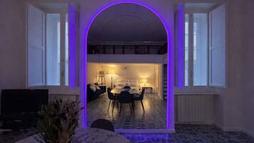 A modern interior with a dining area, kitchen, and a large arched doorway.