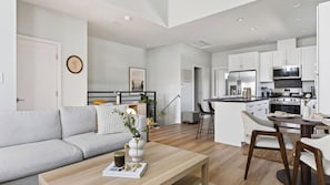 A modern apartment with a living room, dining area, and kitchen.