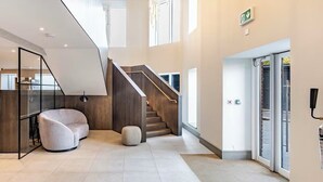 Eine großzügige Lobby mit Treppe, Sitzgelegenheiten und einer Rezeption.