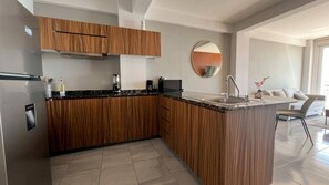 A modern kitchen with wooden cabinetry, a built-in island with a sink, and a round mirror on the wall.
