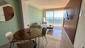 Ein Zimmer mit Esstisch, Stühlen, einer Couch und Meerblick.
