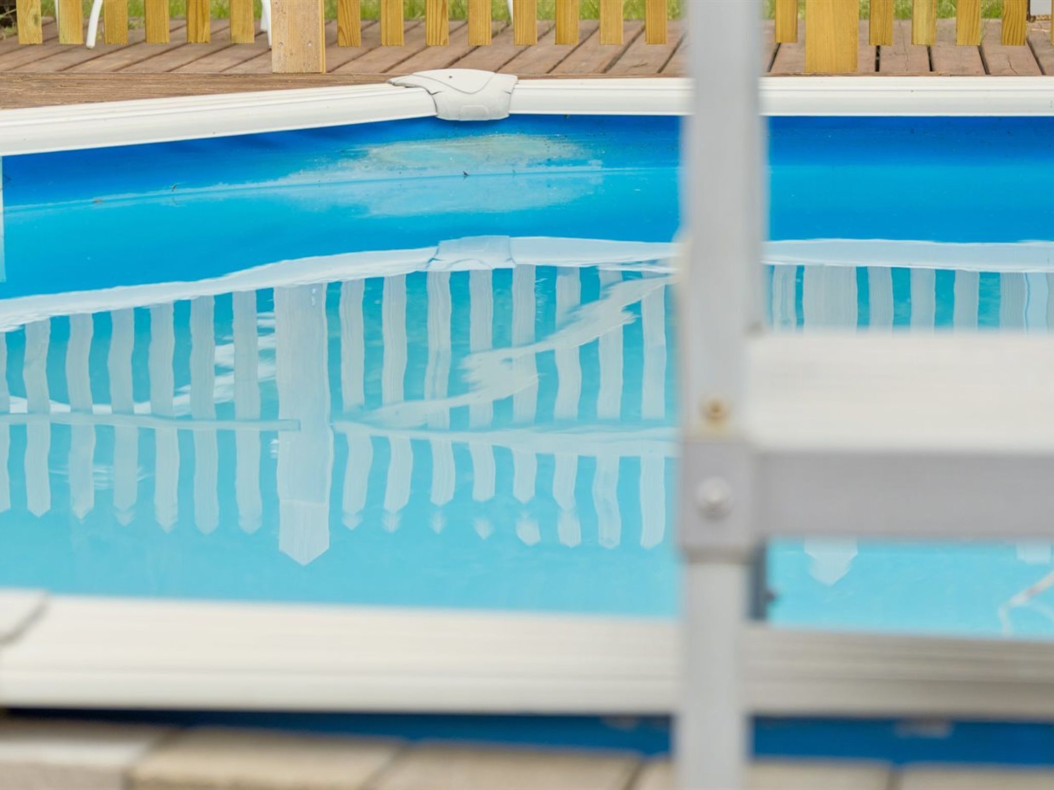 Une piscine dotée d’une terrasse en bois et d’une clôture de sécurité.