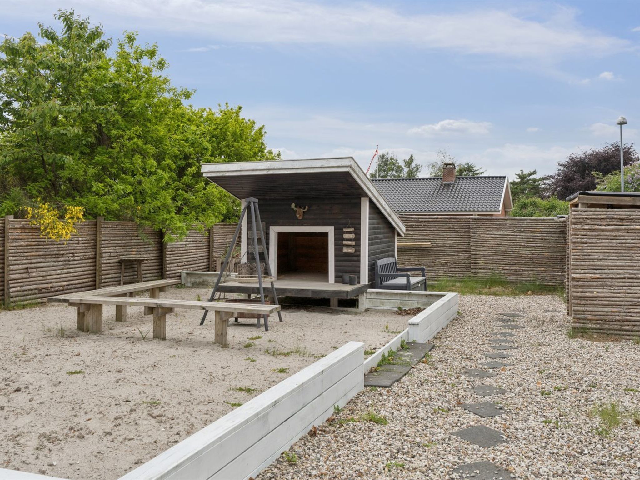 Eine rustikale Holzhütte mit geneigtem Dach, einer Holzdielen-Terrasse und einer Bank.