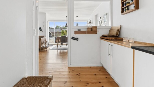 Eine moderne Küche mit weißen Schränken, Holzboden und Blick in den Garten.
