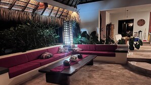 Un salon moderne doté d’un plafond en chaume, d’une grande fenêtre et d’un espace détente avec un canapé et une table basse.