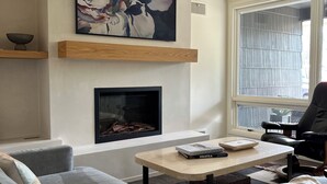 Un salon moderne avec une cheminée, un canapé, une table basse et un tableau au mur.