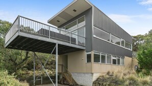 A modern two-story building with a balcony, large windows, and a stone base. - Timbara Hideaway - Ocean Views - Pet Friendly (Fairhaven)