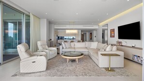 Una sala de estar moderna con un sofá modular, una mesa de centro de vidrio y un televisor de pantalla plana montado en la pared.