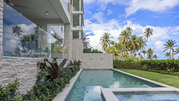 Un edificio moderno con piscina, rodeado de abundante vegetación y palmeras.