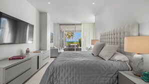 Un dormitorio moderno con una cama grande, un televisor, un escritorio y vistas al exterior.