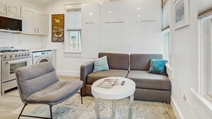 A compact living space with a kitchenette, a sofa, a chair, and a small table. - Cozy Cape Cod Cottage in  Provincetown (Provincetown)