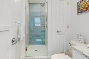 Ein Badezimmer mit einer Duschkabine, einer Toilette und einer Marmorarbeitsplatte.