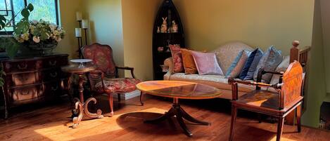A living room with a sofa, armchairs, a coffee table, a wooden cabinet, and a decorative shelf.