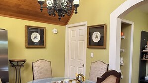 Un coin repas avec une table ronde, des chaises, un lustre et une porte.