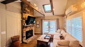 Ein Wohnzimmer mit Kamin aus Stein, einer Couch, einem Couchtisch und einem Fernseher.