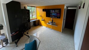 A room with a desk, chair, black wardrobe, and a wall-mounted TV. - Cozy, family and pet-friendly apartment, located right beside a beautiful park. (Bogotá)