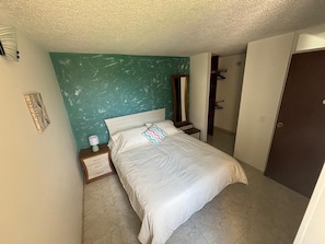 A bedroom with a bed, bedside table, nightstand, and a mirror. - Cozy, family and pet-friendly apartment, located right beside a beautiful park. (Bogotá)