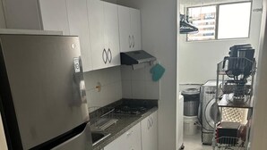 A compact kitchen with a refrigerator, stove, and cabinets. - Cozy, family and pet-friendly apartment, located right beside a beautiful park. (Bogotá)
