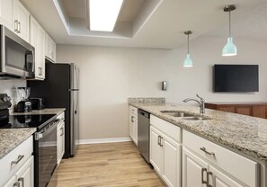 A modern kitchen with granite countertops, stainless steel appliances, and a built-in dishwasher.
