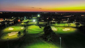 A golf course at dusk with illuminated lights and sand bunkers. - 2 bedroom near Disney with pools and golf courses on the property. (Kissimmee)