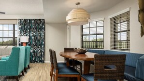 A dining area with a round table, chairs, a hanging light fixture, and a view through the window. - 2 bedroom near Disney with pools and golf courses on the property. (Kissimmee)