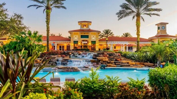 A hotel with a pool, palm trees, and a waterfall. - 2 bedroom near Disney with pools and golf courses on the property. (Kissimmee)