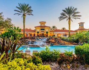 Ein Hotel mit Pool, Palmen und einem Wasserfall.