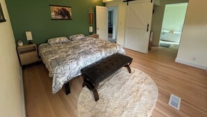 Ein Schlafzimmer mit Bett, Sitzbank, grünen Wänden und einer Schiebetür.