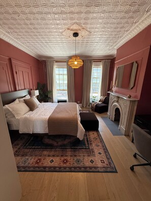 Ein Schlafzimmer mit einem großen Bett, einem Kamin, einer Chandelier und einer gemusterten Decke.