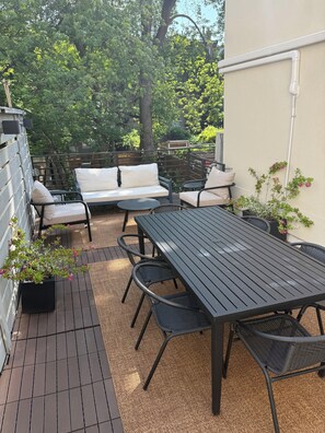 Eine Terrasse mit Tisch, Stühlen, einer Sitzecke und Topfpflanzen.