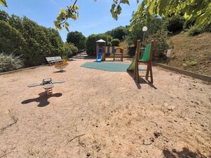 Une aire de jeux avec un toboggan, des balançoires et un banc.