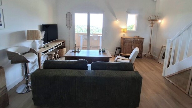 A spacious living area with a sofa, a TV, a dining table, and a staircase. - Cozy apartment with a view of the sea and the pool in a private residence. Pets Allowed (Roquebrune-sur-Argens)