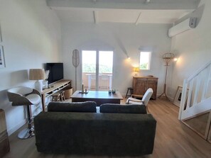 Un vaste espace de vie comprenant un canapé, un téléviseur, une table à manger et un escalier.