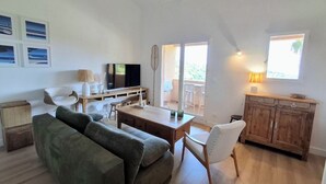 A spacious living area with a sofa, dining table, and wooden cabinets. - Cozy apartment with a view of the sea and the pool in a private residence. Pets Allowed (Roquebrune-sur-Argens)