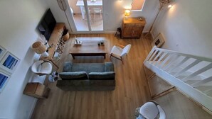 A spacious living area with a sofa, chairs, a dining table, and a TV. - Cozy apartment with a view of the sea and the pool in a private residence. Pets Allowed (Roquebrune-sur-Argens)