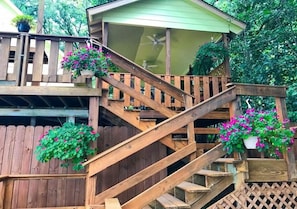 A wooden deck with a staircase leading to a covered area with a ceiling fan.