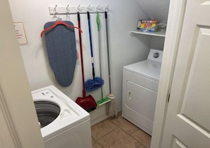 A laundry area with a washing machine, a drying rack, and a mop rack.