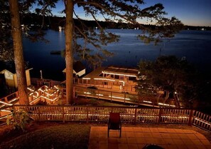 A waterfront property with a wooden deck, a chair, and a view of the lake.