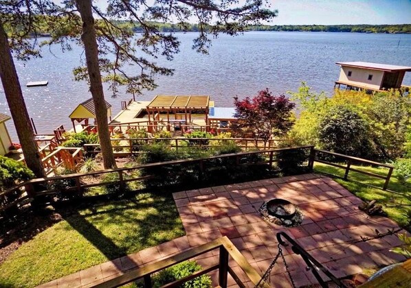 A deck with a fire pit, overlooking a lake with a boat in the distance.